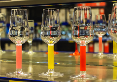 Rainbow transparent colored wine glasses green and blue and orange colors with beautiful reflections are on a mirror glass backgroundの写真素材