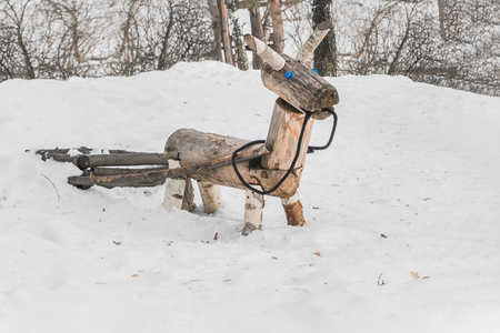 A wooden yellow horse or donkey with a carriage for children is on the playground in the winter parkの写真素材