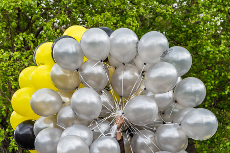 A group of yellow and white air pearl balls is in the man hand for decoration outside in summerの写真素材