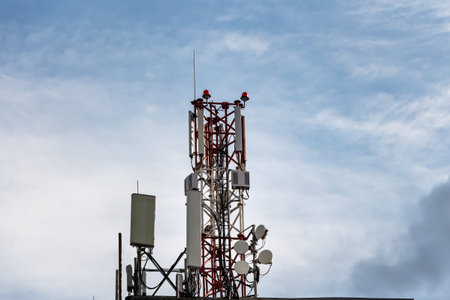 There is one gray and red Radio relay tower with group of different cellular and satellite antennas...