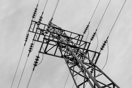 A rusty power line is on the blue sky background. Black and white photo