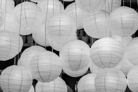 A group of round beautiful white paper burning lamps is on the gray background inside. Black and whiteの写真素材