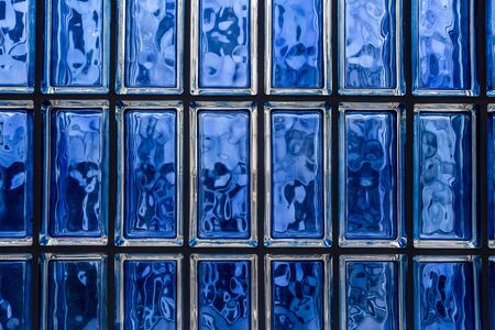 A beautiful horizontal texture of part of a white glass transparent square brick wall in blue hue is on the photoの写真素材
