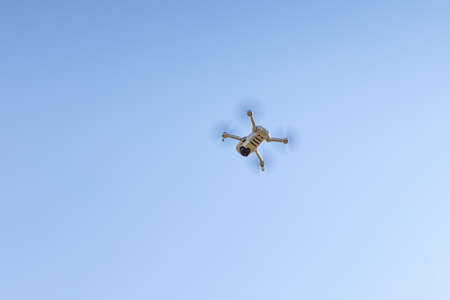 The White unmanned aerial vehicle with four propellers and blades is in the blue sky backgroundの写真素材