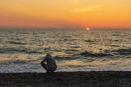Beautiful orange sunrise is on the beach by the sea with black ship silhouettes and a man on a beach