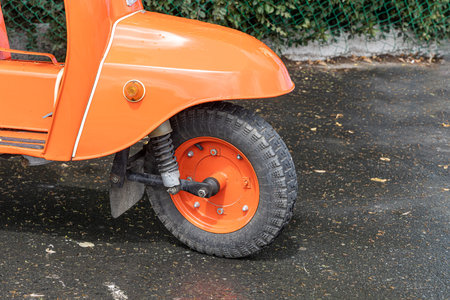 An Orange and black motorcycle stands on a gray asphalt