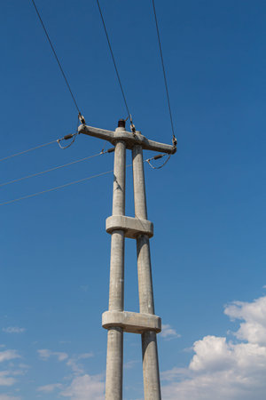 A Concrete transmission tower line is on the blue sky background. Vertical