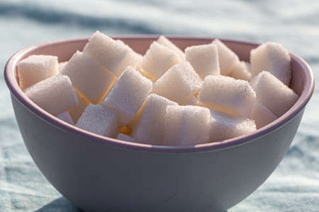 The cubic sugar lumps are in the brown bowlの写真素材