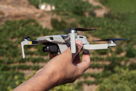 A Man is launching a gray drone with a with four propellers and blades in his hands in sunny summer...