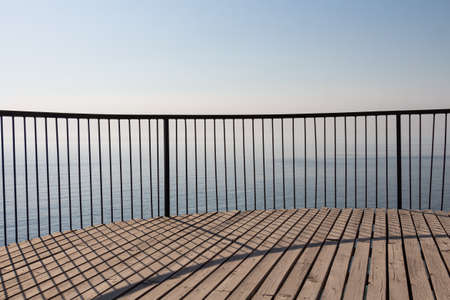 Beautiful wooden terrace with a metal fence is on the beach by the blue seaの写真素材