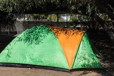 Green and orange tent is on a ground in the campingの写真素材