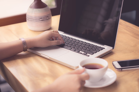 woman working on laptop and drinking coffee, Business woman have a coffee and working in time, Business financial working conceptの写真素材