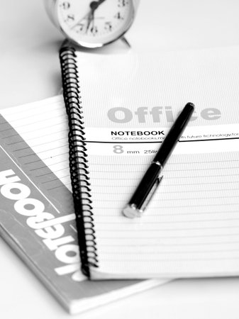 Pen, books and alarm clock on white background