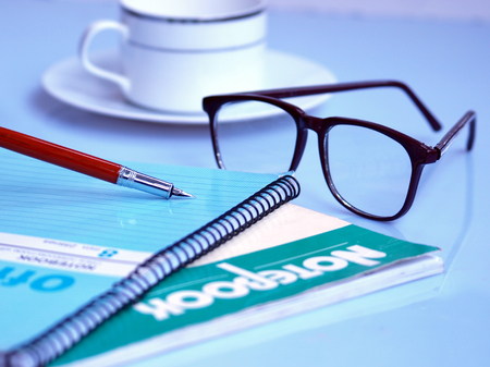Pen, books and a spec on tableの写真素材