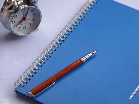 Pen, books and alarm clock on tableのeditorial素材