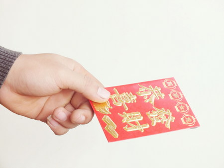 A hand holding Chinese red packetsの写真素材