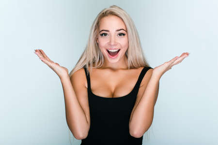 Have you seen it? Beautiful young woman with blond hair looking excited while standing against gray backgroundの写真素材