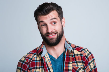 Really? Portrait of handsome young man looking sarcastic while standing against white background