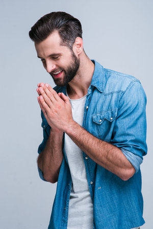 Peaceful smile. Handsome young man looking away with smile and keeping arms crossed while standing...