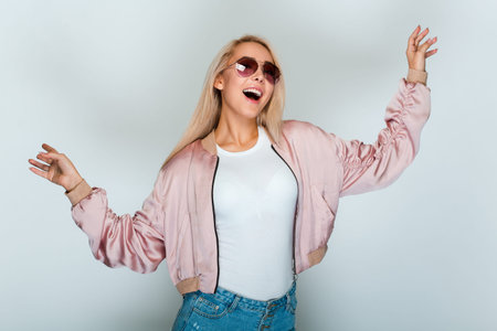 Make a little dance. Beautiful young woman with blond hair looking at camera with smile while...
