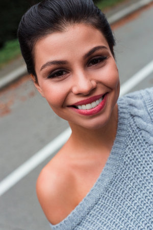 Portrait of beauty. Beautiful young woman in sweater looking at camera with smile while standing...