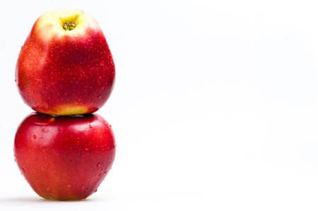 two red apples on white background on the leftの写真素材