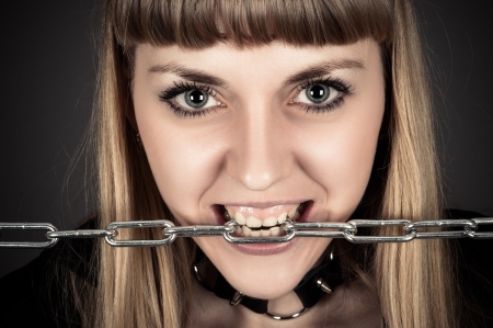 portrait of a brutal woman with a chain in teethの写真素材