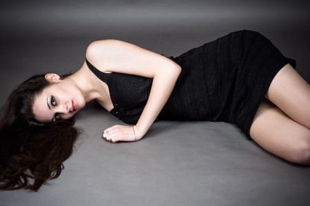 attractive woman lying on the floor in a black dressの写真素材