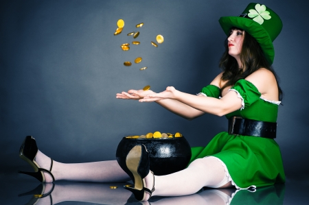 a woman dressed as a leprechaun gold coin throws upの写真素材