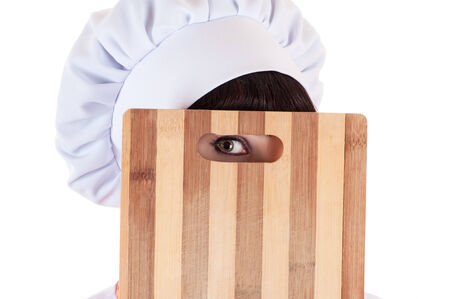 chef looking with one eye through a a cutting boardの写真素材