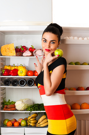 attractive woman in dress standing at the fridgeの写真素材