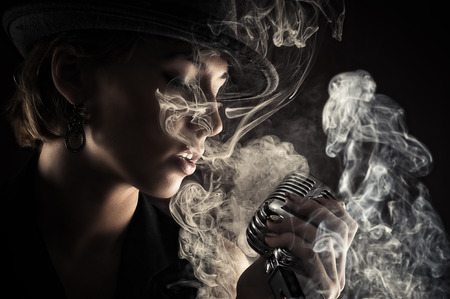 singer woman with retro microphone in smokeの写真素材