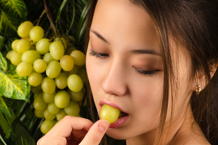 Korean beautiful girl eating grapes closeupの写真素材