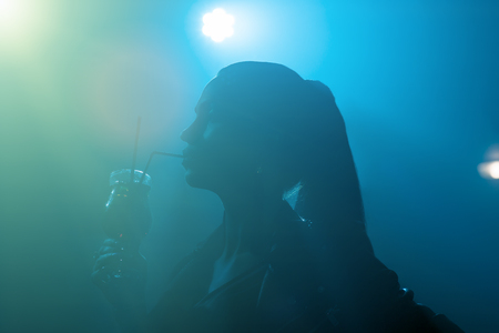 silhouette beautiful brunette drinking alcohol in clubの写真素材