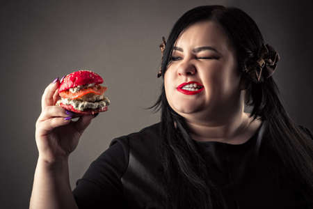 portrait attractive fat woman eating red hamburgerの写真素材
