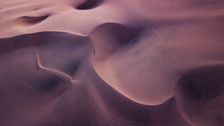 Aerial top-down view of sand dunes during the sunset creating abstract shapes due to wind...