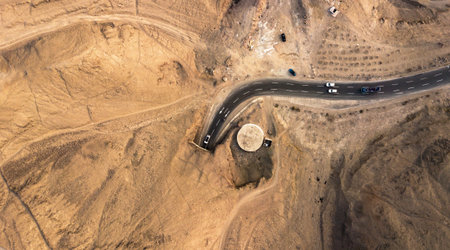 Aerial view on a tunnel through the mountain with cars passing by in the desert during the sunset.