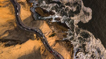 Aerial top-down view on the road at the cliffs next to the rocky coast with traffic during the sunset, Chorillos, Lima, Peru.の写真素材