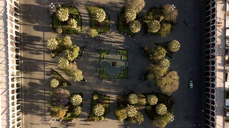 Top down close up aerial view of Arequipa's white city main square geometric park with arches on sides. Sunset time - shadows of trees and people walking.の写真素材