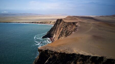 Aerial view of Playa Roja cliffs in Paracas, Peru - brown sand, golden rocks, green water, sunny weatherの写真素材