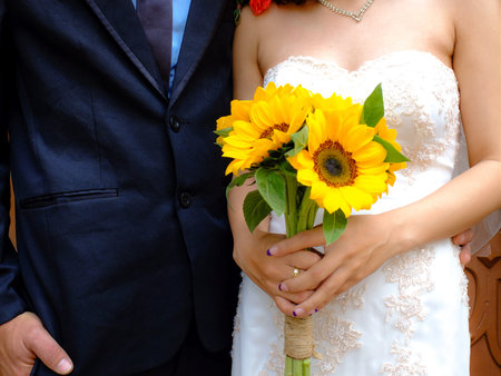 Bride holding wedding bouquet flowers against dressの写真素材