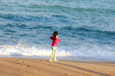 Nha Trang city Vietnam January 27 2014: Unknown Little cute girl running on the white sandy beach in Nha Trang Vietnam proved to be extremely excited SHE enjoy the sea wavesのeditorial素材