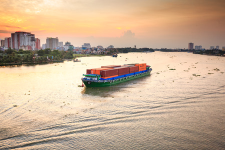 Hochiminhcity Vietnam June 3 2015: Maritime transport loading container vessel on river water on residential and apartment scene at riverside industrial city of Vietnam June 3 2015のeditorial素材