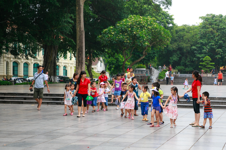 Hanoi City, Vietnam - June 18, 2014: Two young teachers of the kindergarten was crossing a street Guiding the Children in Ha Noi - Vietnamのeditorial素材