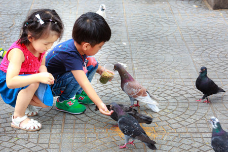Hochiminh City, Vietnam - July 14, 2015: two babies for feeding pigeons on the streets of Saigonのeditorial素材