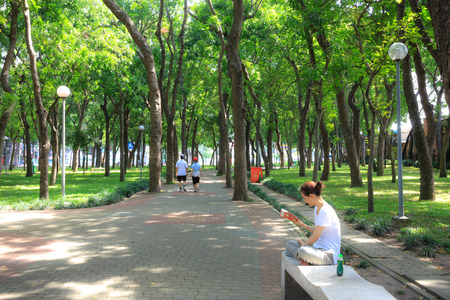 Ho Chi Minh city, Viet nam - July 5, 2015: Unknown, a woman is reading book relaxing on a bench in a park in Ho Chi Minh Cityのeditorial素材
