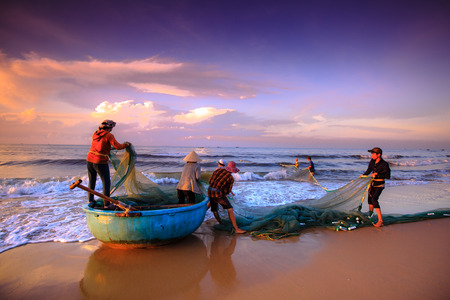Beach Lagi, Binh Thuan province, Vietnam - August 29, 2015: Unknown Fishermen who pull up th are the fishing nets khi sunrise. This is ask for their daily workのeditorial素材