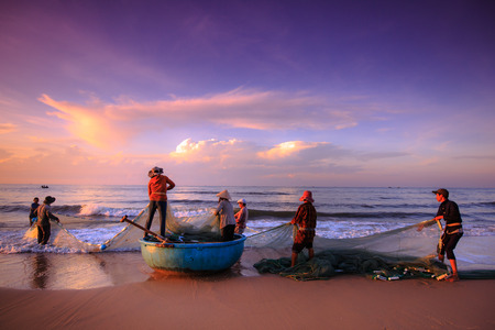 Beach Lagi, Binh Thuan province, Vietnam - August 29, 2015: Unknown Fishermen who pull up th are the fishing nets khi sunrise. This is ask for their daily workのeditorial素材