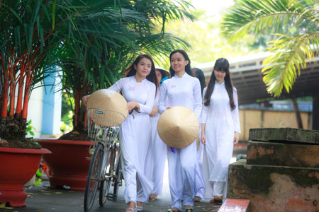 Hochiminh City, Vietnam - September 13, 2015: Unidentified Vietnamese Ao dai girls wear white uniform at c schoolyard. Ao dai is famous for traditional Custume woman in Vietnam.のeditorial素材