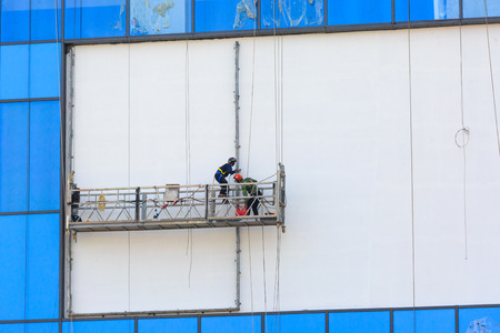 Hochiminh City, Vietnam - September 19, 2015: Dangerous job of the workers cleaning the glass surface m of a new building completedのeditorial素材